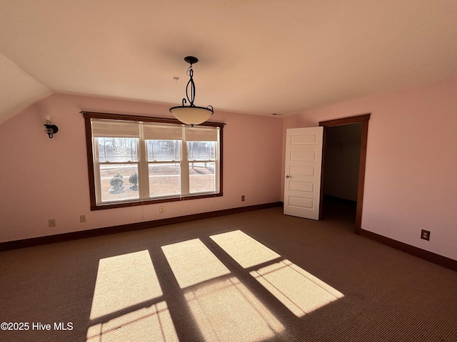 unfurnished bedroom featuring lofted ceiling and dark carpet