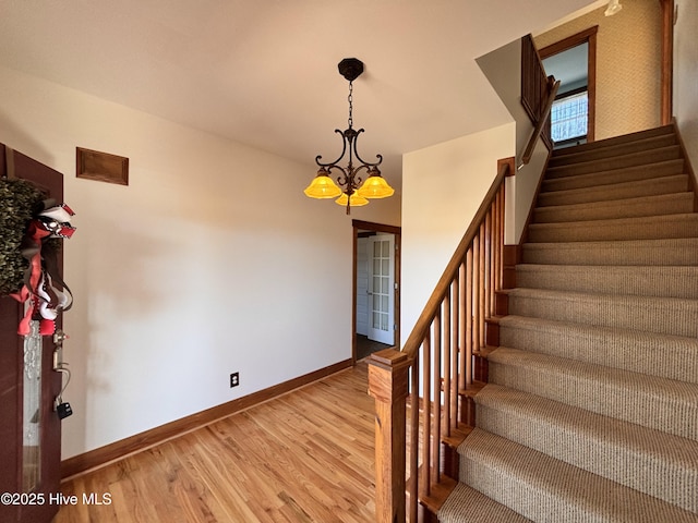 stairway with hardwood / wood-style flooring and a chandelier