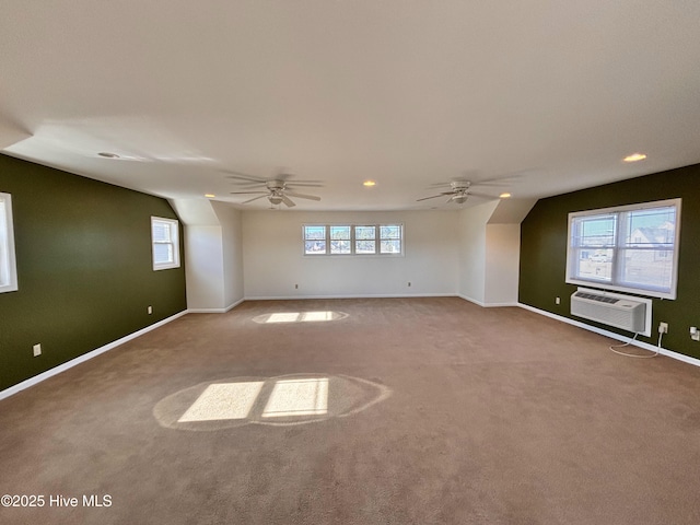 carpeted empty room featuring ceiling fan, a wall unit AC, and a wealth of natural light