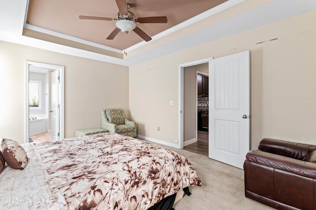 carpeted bedroom featuring a raised ceiling, crown molding, ceiling fan, and ensuite bath