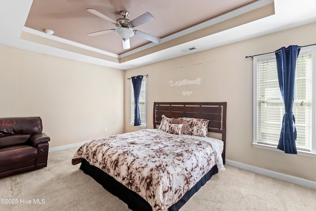 bedroom with ornamental molding, light colored carpet, a raised ceiling, and ceiling fan