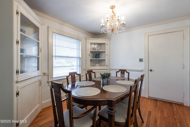 dining space with ornamental molding, hardwood / wood-style floors, and a notable chandelier