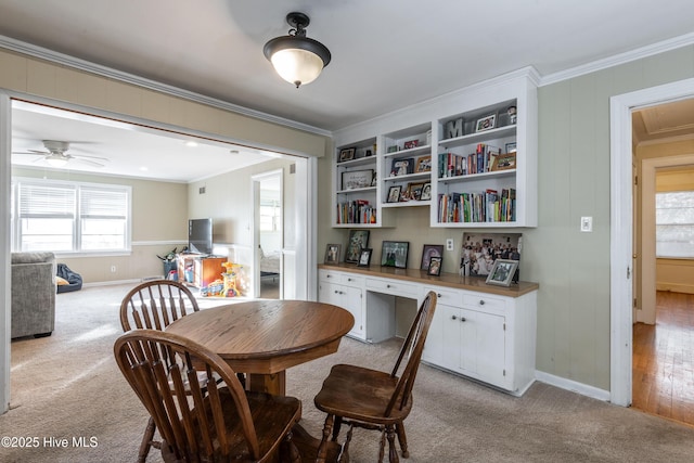 dining space with crown molding, light colored carpet, and built in desk