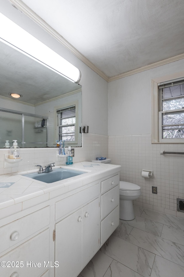 bathroom with walk in shower, toilet, tile walls, ornamental molding, and vanity