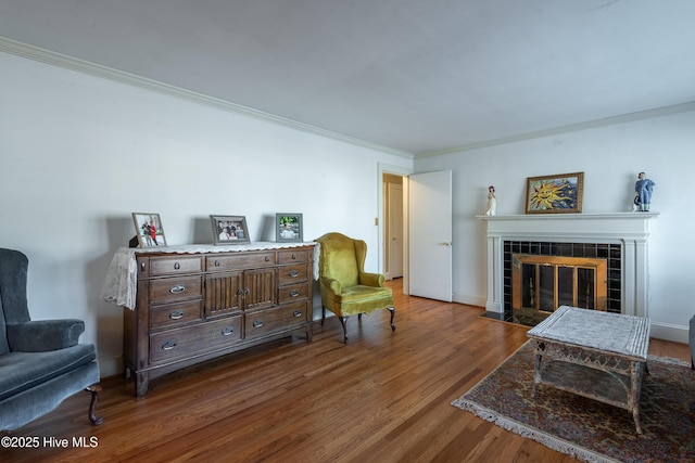 living area featuring a tile fireplace, dark wood-type flooring, and ornamental molding