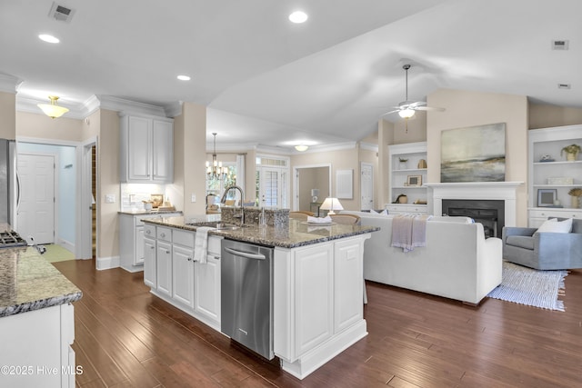 kitchen with a center island with sink, dark stone counters, white cabinets, and appliances with stainless steel finishes