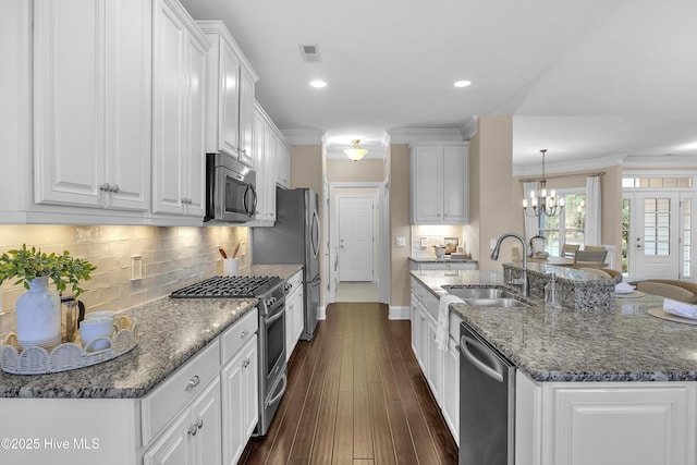 kitchen with sink, white cabinetry, a kitchen island with sink, stainless steel appliances, and ornamental molding