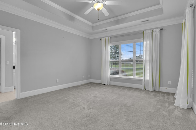 unfurnished room featuring ornamental molding, light colored carpet, ceiling fan, and a tray ceiling