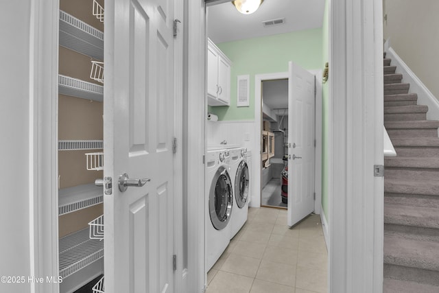 washroom with separate washer and dryer, light tile patterned floors, and cabinets