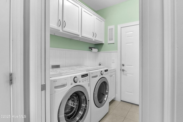 laundry area with light tile patterned floors, washing machine and dryer, and cabinets