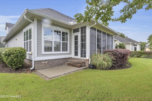 back of house featuring a patio, a sunroom, and a lawn