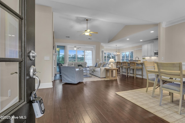 living room featuring hardwood / wood-style floors, a wealth of natural light, ornamental molding, and vaulted ceiling