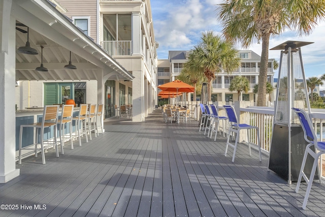 wooden terrace featuring ceiling fan and a bar