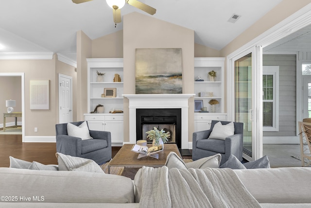 living room featuring built in shelves, lofted ceiling, crown molding, dark hardwood / wood-style flooring, and ceiling fan