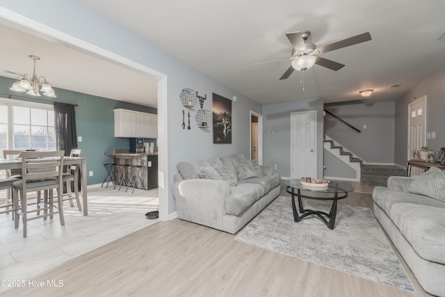 living room with ceiling fan with notable chandelier and light hardwood / wood-style flooring