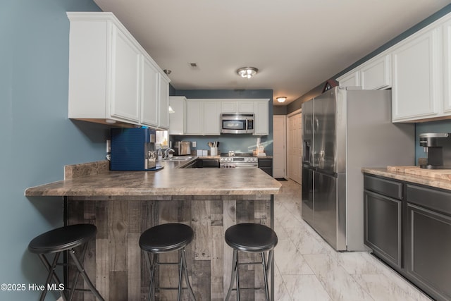 kitchen featuring sink, a kitchen breakfast bar, white cabinets, and appliances with stainless steel finishes