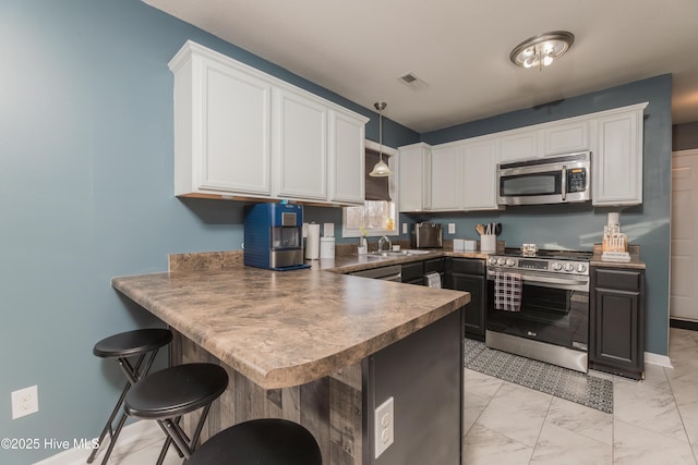 kitchen featuring white cabinetry, kitchen peninsula, and appliances with stainless steel finishes