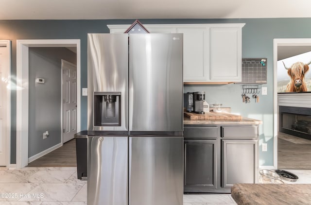 kitchen featuring stainless steel fridge and white cabinets