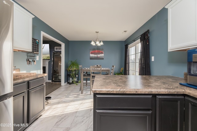 kitchen with white cabinetry, hanging light fixtures, and a chandelier