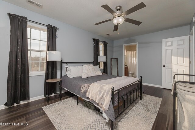 bedroom featuring ensuite bathroom, dark wood-type flooring, and ceiling fan