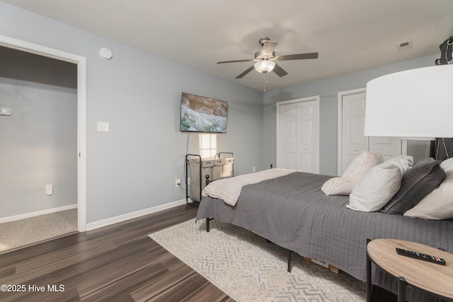 bedroom featuring dark wood-type flooring, two closets, and ceiling fan