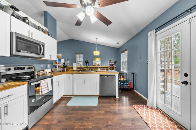 kitchen with hanging light fixtures, stainless steel appliances, kitchen peninsula, and white cabinets