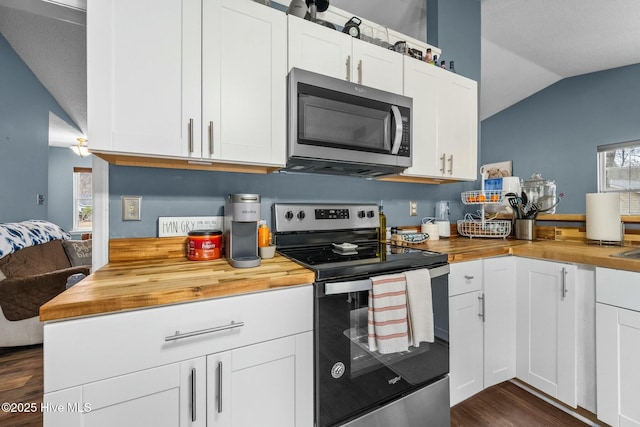 kitchen featuring dark wood-type flooring, appliances with stainless steel finishes, white cabinetry, wood counters, and vaulted ceiling