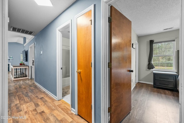 hallway with hardwood / wood-style flooring and a textured ceiling