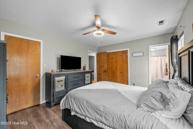 bedroom with dark hardwood / wood-style flooring, ceiling fan, and a textured ceiling