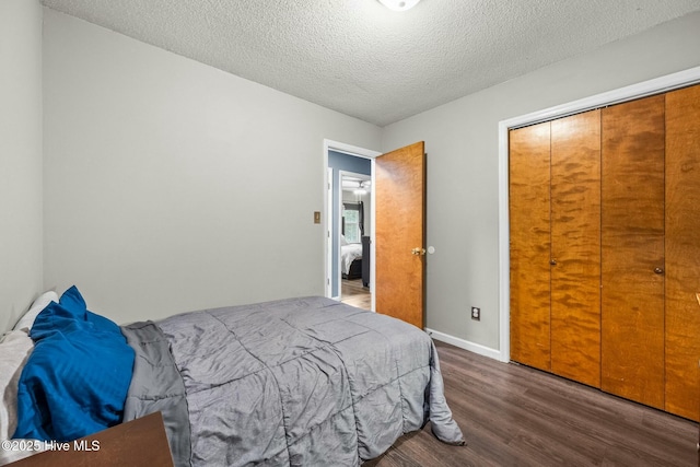 bedroom featuring dark wood-type flooring, a textured ceiling, and a closet