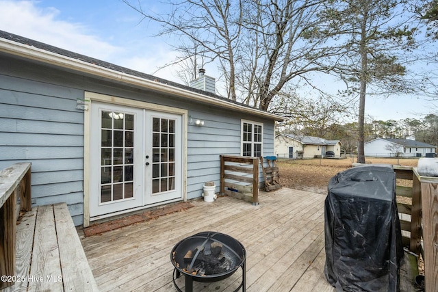 wooden deck with french doors, area for grilling, and an outdoor fire pit