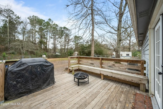 wooden terrace with area for grilling and an outdoor fire pit