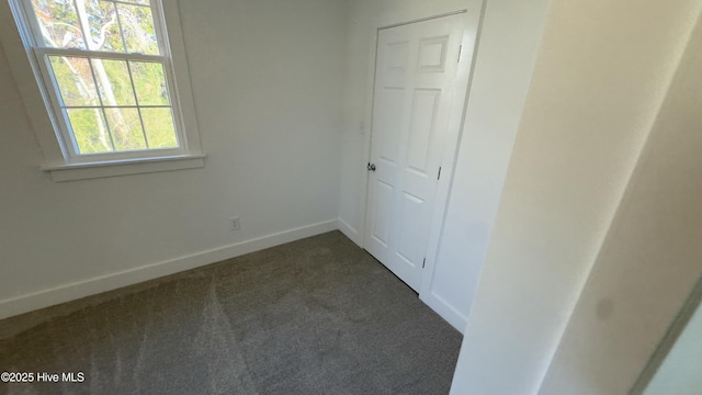 unfurnished bedroom featuring dark carpet and a closet