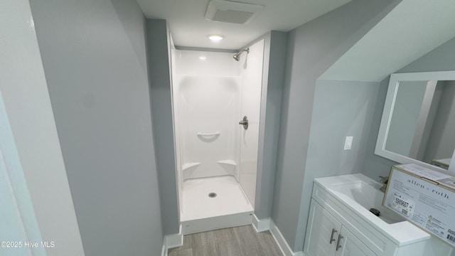 bathroom with walk in shower, vanity, and hardwood / wood-style flooring