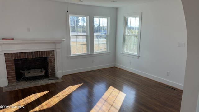 unfurnished living room with a brick fireplace and dark hardwood / wood-style flooring