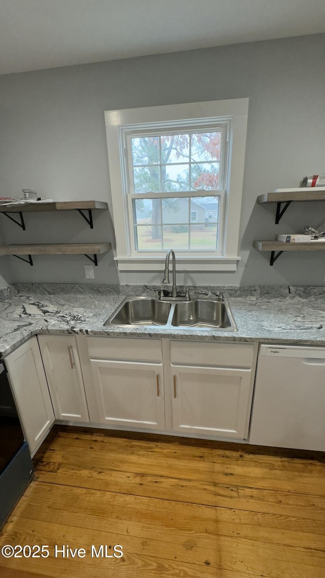 kitchen with light hardwood / wood-style floors, dishwasher, sink, and white cabinets