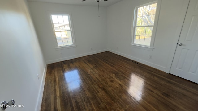 unfurnished room with dark wood-type flooring, ceiling fan, and a healthy amount of sunlight