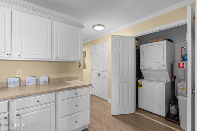 laundry area with light hardwood / wood-style floors, ornamental molding, electric water heater, and stacked washer / dryer