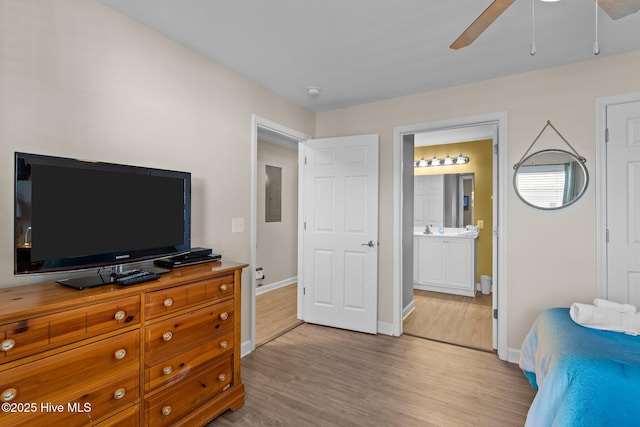 bedroom with ceiling fan, ensuite bath, electric panel, and light wood-type flooring