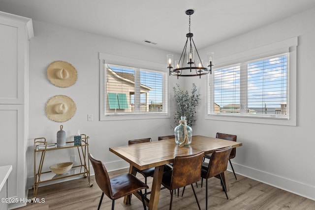 dining area featuring wood-type flooring and a notable chandelier