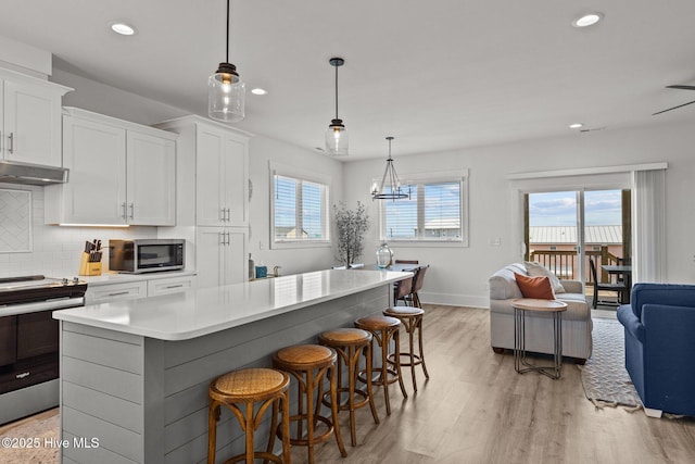 kitchen with white cabinetry, stainless steel appliances, decorative light fixtures, and a center island