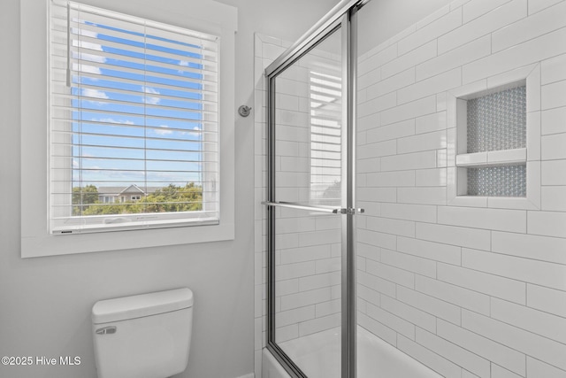 bathroom with bath / shower combo with glass door and toilet