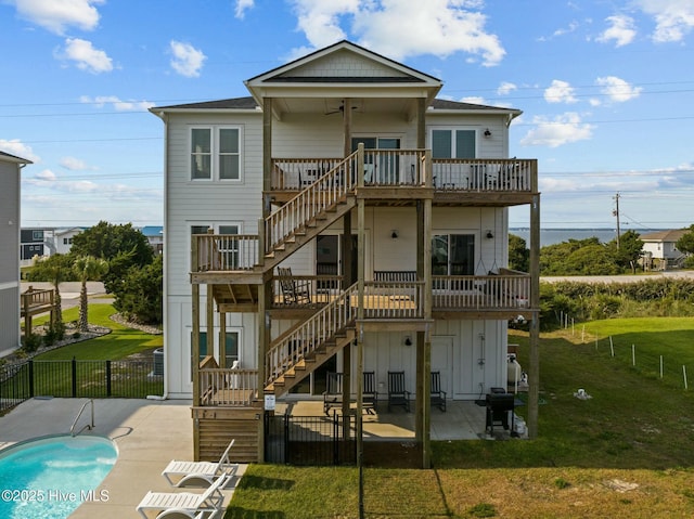 rear view of property featuring a yard, a patio area, ceiling fan, and a swimming pool side deck