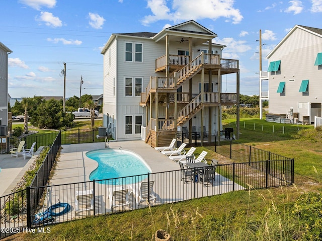 back of house featuring ceiling fan, a fenced in pool, a patio area, and a lawn