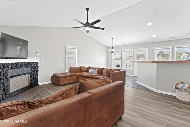 living room with a fireplace, wood-type flooring, ceiling fan, and vaulted ceiling