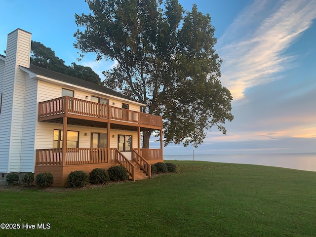 back house at dusk featuring a yard and a deck