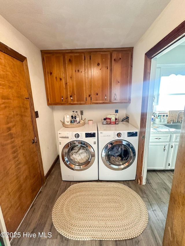 washroom featuring hardwood / wood-style flooring, cabinets, washer and clothes dryer, and sink