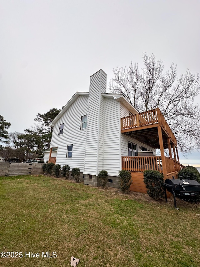 view of side of property featuring a wooden deck and a lawn