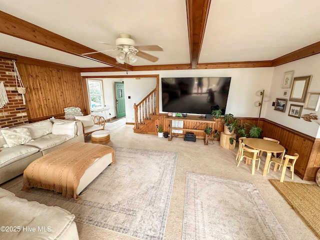 carpeted living room featuring ceiling fan, wooden walls, and beam ceiling