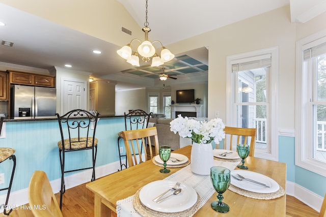 dining area with ornamental molding, coffered ceiling, ceiling fan with notable chandelier, and light wood-type flooring